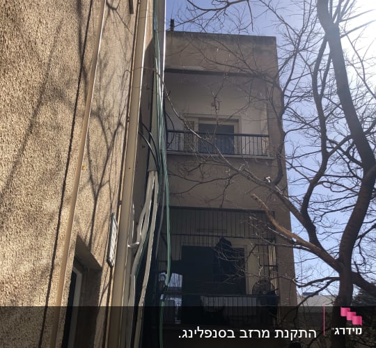 כבלים וצינורות תלויים על קיר בניין